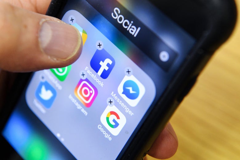 A man holds a smart phone with the icons for the social networking apps Facebook, Instagram and Twitter.